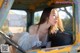 A woman in a white dress is sitting in an old truck.