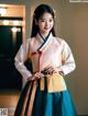 A woman in a blue and white hanbok poses for a picture.