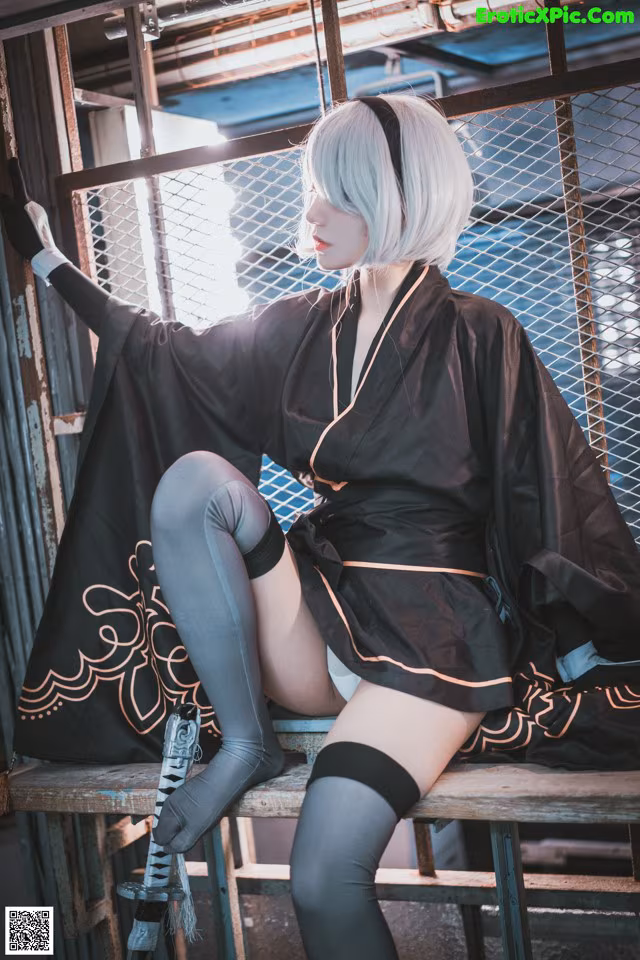 A woman in a black kimono sitting on a bench.