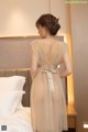 a woman in a beige dress standing on a bed